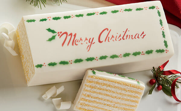 Cream Colored Dobosh Torte with Merry Christmas written on top in Red