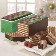 Two chocolate dobosh torte cakes, one in a gift box with sliced pieces of dobosh torte on the side