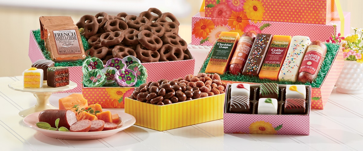 Spring Daisy Tower: five colorful gift boxes containing a variety of cheeses, sausages, baked goods and other treats stacked in a tower and tied together with a yellow ribbon